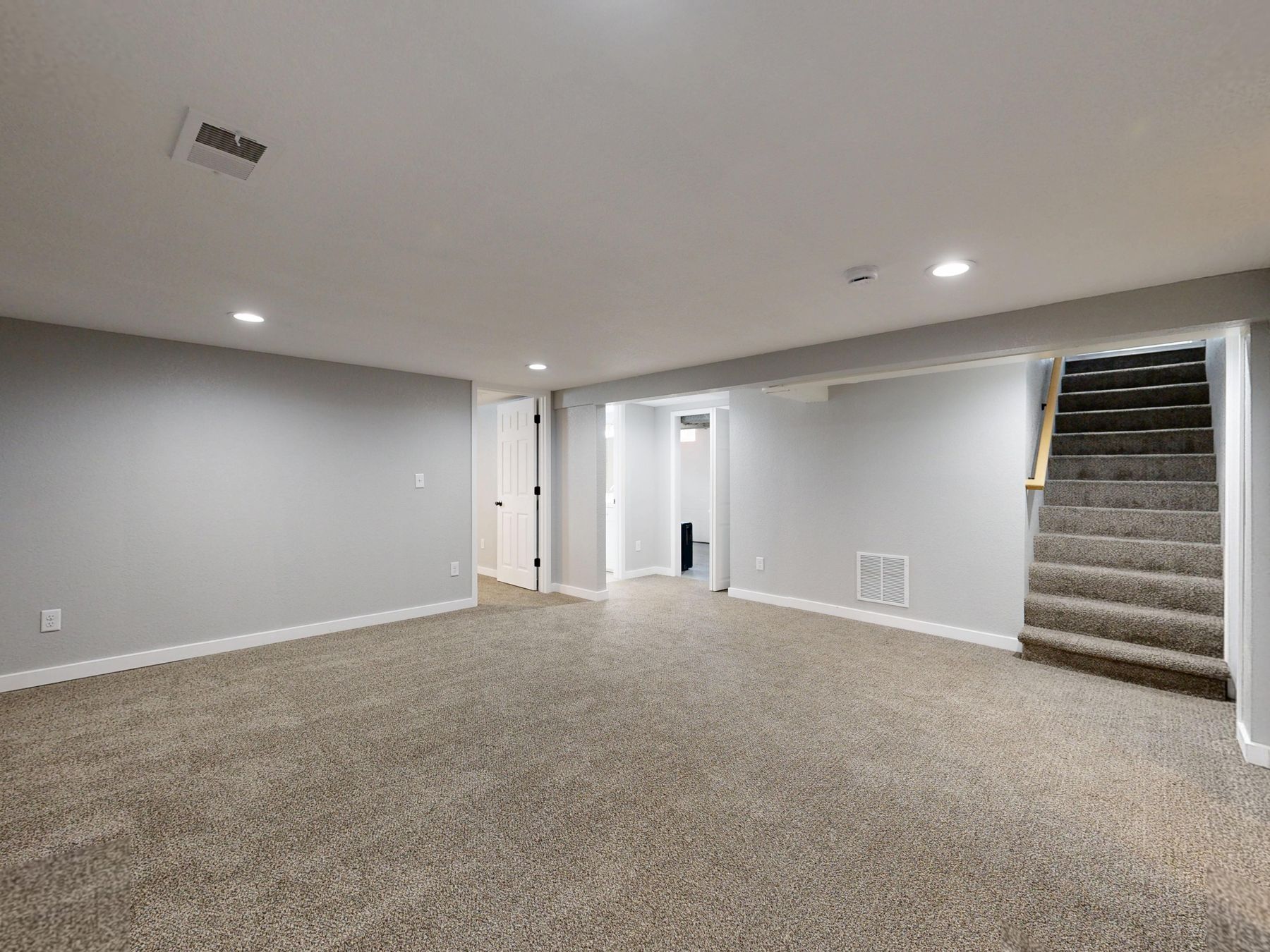 A finished basement living space with recessed lighting