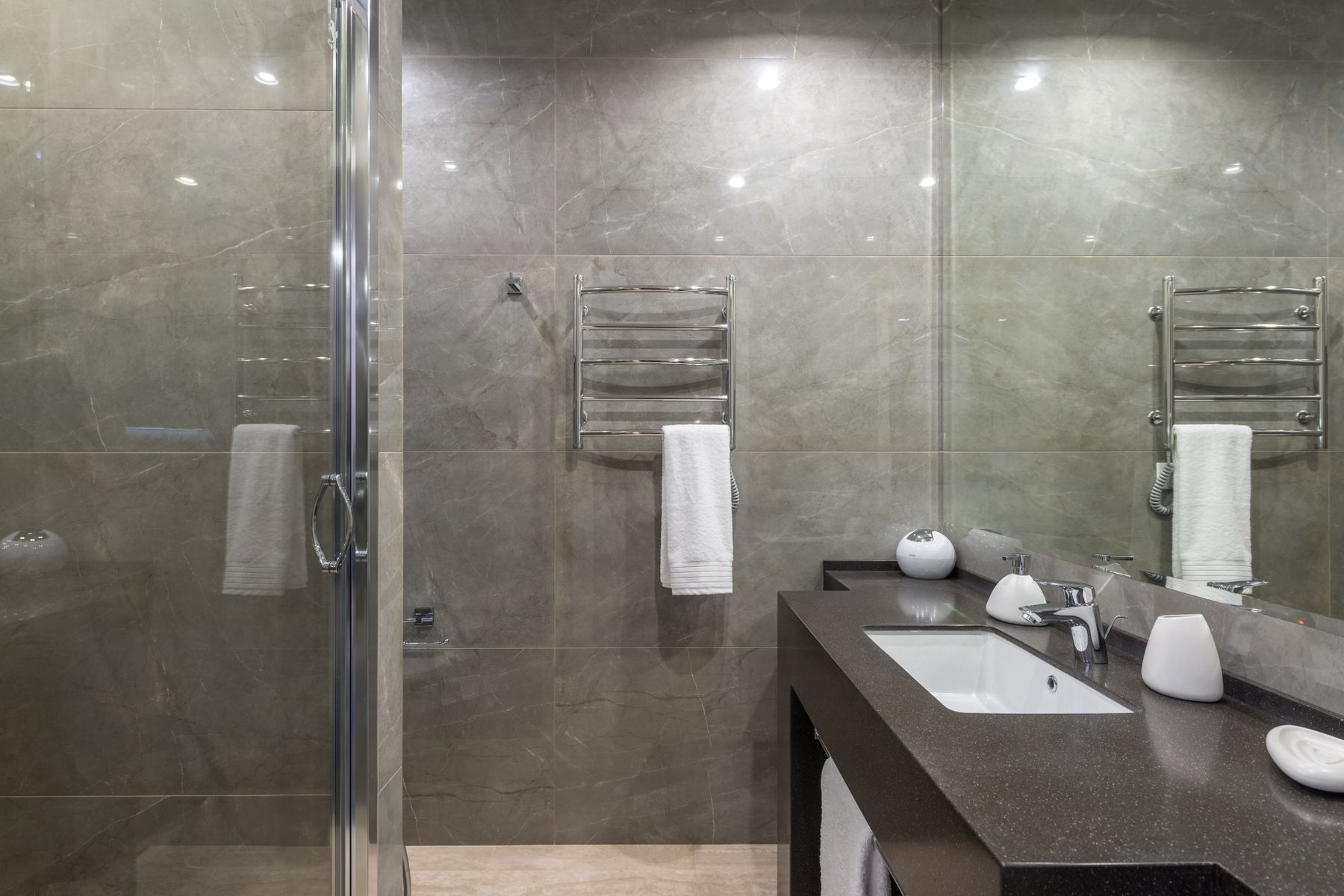 A finished bathroom renovation with tiled walls and a glass shower screen